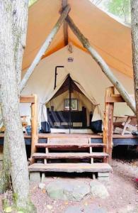 a tent with a bed and stairs in it at Rustic Safari Tent for a Unique Glamping Experience near Gore Mountain, New York in North Creek