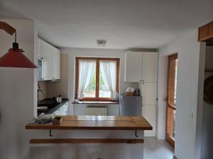 a kitchen with white cabinets and a wooden table at La MaisonB - Arly in La Thuile