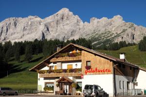 a building with a sign on it with mountains in the background at Rifugio Palafavera in Val di Zoldo