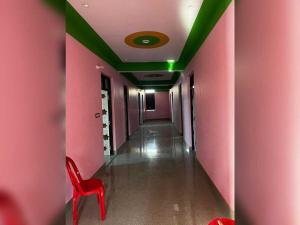 a corridor with pink walls and a red chair in a hallway at SPOT ON Dream Guest House in Kankather