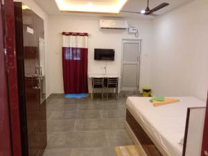 a room with a bed and a table and a tv at SPOT ON Khushi Lodge in Kurua