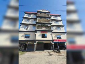a tall white building with a motorcycle parked in front of it at SPOT ON Khushi Lodge in Kurua