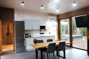 a kitchen with a table with chairs and a refrigerator at Metsamajake Hubert sauna ja mullivanniga looduse keskel in Sigula