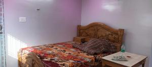 a bedroom with a bed with a wooden headboard and a table at SPOT ON Hotel Parvati Resort in Suitha