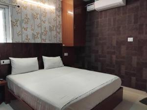 a bedroom with a large bed with white sheets at Hotel O Kilambakkam New Bus Terminal Formerly TAD Homes in Urapakkam