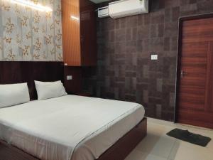 1 dormitorio con cama blanca y pared en Hotel O Kilambakkam New Bus Terminal Formerly TAD Homes, en Urapakkam
