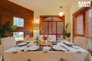 a dining room with a table with plates and wine glasses at StayVista at Moets Palm Villa with BBQ & Bonfire in Gurgaon
