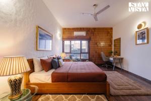 a bedroom with a bed and a desk and a window at StayVista at Moets Palm Villa with BBQ & Bonfire in Gurgaon