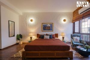 a bedroom with a large bed and a chair at StayVista at Moets Palm Villa with BBQ & Bonfire in Gurgaon +86 photos