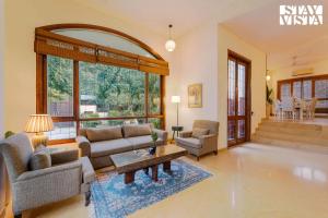 a living room with a couch and chairs and a table at StayVista at Moets Palm Villa with BBQ & Bonfire in Gurgaon