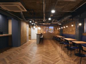 a row of tables and chairs in a room with wooden floors at Shijo Guesthouse HIVE in Kyoto