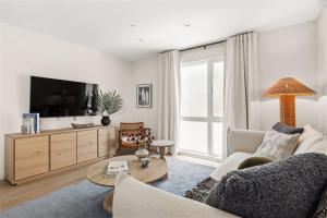 Una sala de estar con un sofá y un televisor. en Tide House - Unit B - Modern Seaside 1BD w Parking, en El Segundo