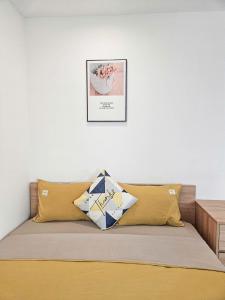 1 cama con almohadas amarillas y una foto en la pared en DeepHome - Trinh Cong Son, en Hanói