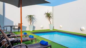a swimming pool with chairs and an umbrella at The Edward in Durban