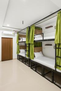 Habitación con 4 literas y cortinas verdes. en SAIR Hostel, Varanasi - 100m from Assi Ghat, en Varanasi