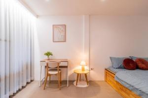 une chambre avec un lit, une table et un bureau dans l'établissement Minimal House Maximum Happiness, à Thung Maha Mek
