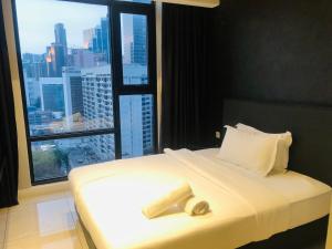 ein Bett in einem Zimmer mit einem großen Fenster in der Unterkunft Axon Residence Popular Suite Kl in Kuala Lumpur