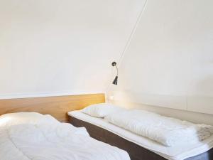 two beds in a room with white walls at 5 person holiday home on a holiday park in Gudhjem in Gudhjem