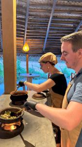 Un hombre y una mujer cocinando en una estufa en Richards Cabanas, en Tissamaharama