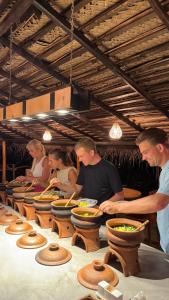 un grupo de personas preparando comida en una cocina en Richards Cabanas, en Tissamaharama