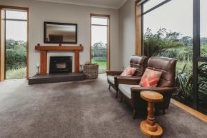 a living room with two chairs and a fireplace at Serenity Lodge Getaway - with river views in Egmont Village