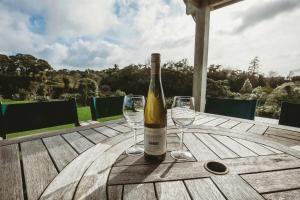 a bottle of wine sitting on a wooden table with two glasses at Serenity Lodge Getaway - with river views in Egmont Village +13 photos