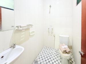 a white bathroom with a toilet and a sink at RedDoorz near Jawa Timur Park 1 in Batu