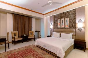 a hotel room with a bed and a desk and a table at Shelton's Rezidor Peshawar in Peshawar