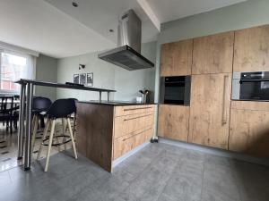 une cuisine avec des placards en bois et un bar avec des tabourets dans l'établissement Rétro Lomme, à Lille