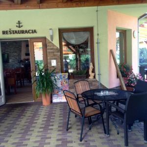 a patio with a table and chairs in front of a restaurant at Penzión Kotva Prístav in Námestovo