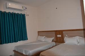two beds in a room with a green curtain at Malwa resort in Chitrakoot