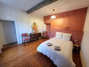 ein Schlafzimmer mit einem weißen Bett, einem Tisch und einem Stuhl in der Unterkunft Grand Gîte au cœur du village avec jardin in Regny