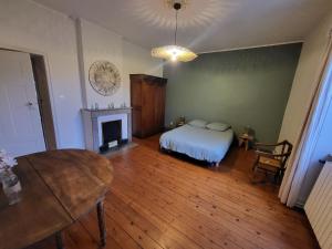 Schlafzimmer mit einem Bett, einem Tisch und einem Kamin in der Unterkunft Grand Gîte au cœur du village avec jardin in Regny