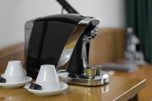 een koffiezetapparaat en twee kopjes op een tafel bij Hotel Nickisch in Schüttorf