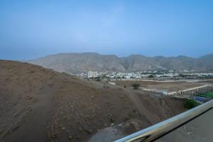 a view of a desert with a city and mountains at شقة فندقية جميلة و مخصصة للايجار لشخصين في بوشر - مسقط - القرم in Jāl