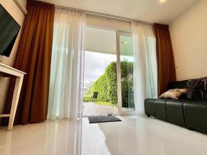 a living room with a couch and a large window at Cozy Garden Apartment Butterfly Karon beach in Ban Karon