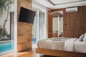 a bedroom with a bed and a tv on a wall at Sana Vie Villa Seminyak by Ini Vie Hospitality in Seminyak +28 photos