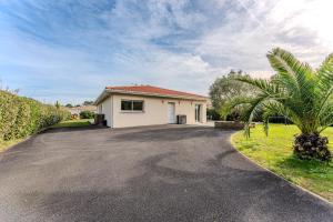 una entrada con una casa y una palmera en Villa piscine entre lac et océan, en Cazaux