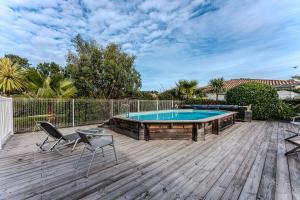 un patio con piscina y sillas en una terraza de madera en Villa piscine entre lac et océan, en Cazaux