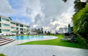 a swimming pool with chairs and a building at Cozy Garden Apartment Butterfly Karon beach in Ban Karon