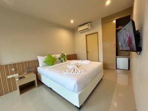 a bedroom with a white bed with a tv on the wall at Transit Samui Resort in Koh Samui