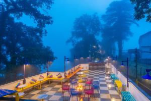 a patio with tables and chairs and lights at night at goSTOPS Mussoorie Clock Tower in Mussoorie