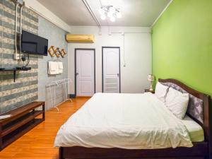 a bedroom with a white bed and a green wall at Thepmongkol House in Bangkok