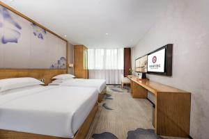 深セン市にあるMotri莫里宝乐城市酒店のベッド2台とテレビがあるホテルの部屋