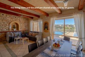 a living room with a table and chairs and a living room at Hibiscus in Xagħra
