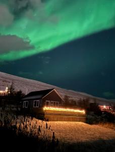 una casa con las verdes luces del norte en el cielo en Veigakot, en Akureyri