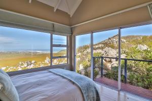 Un dormitorio con una cama y grandes ventanales. en Tranquility Heights, en Pringle Bay