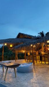 un patio con una mesa y una sombrilla de paja en Richards Cabanas, en Tissamaharama