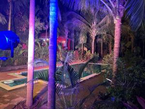 a resort with palm trees and a pool with purple lights at Savali farm stay in Parchuri