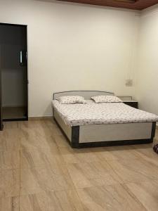 a bed in a white room with a wooden floor at Savali farm stay in Parchuri